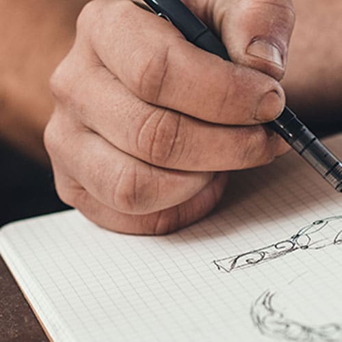 photograph of hand with a pen desiging a ring